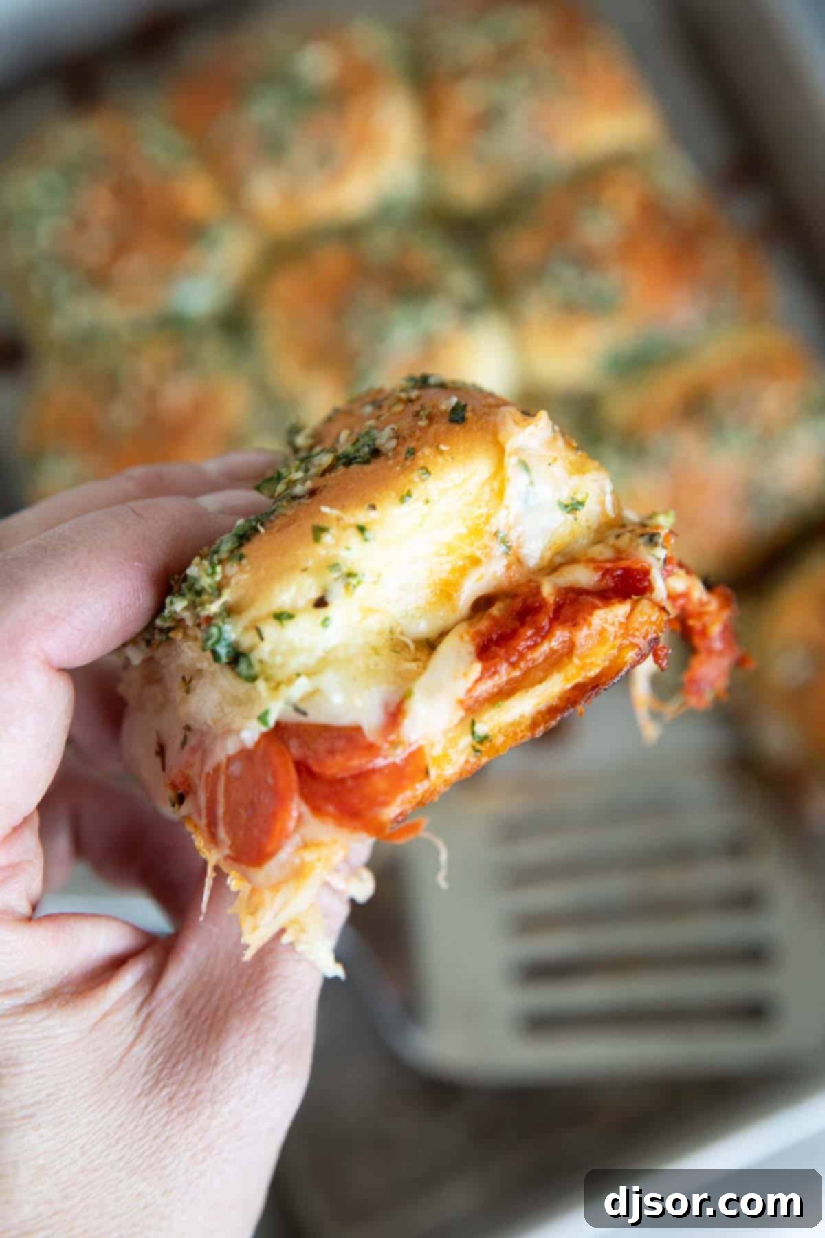 Pepperoni Pizza Poppers 9 Hand holding a pepperoni pizza slider.