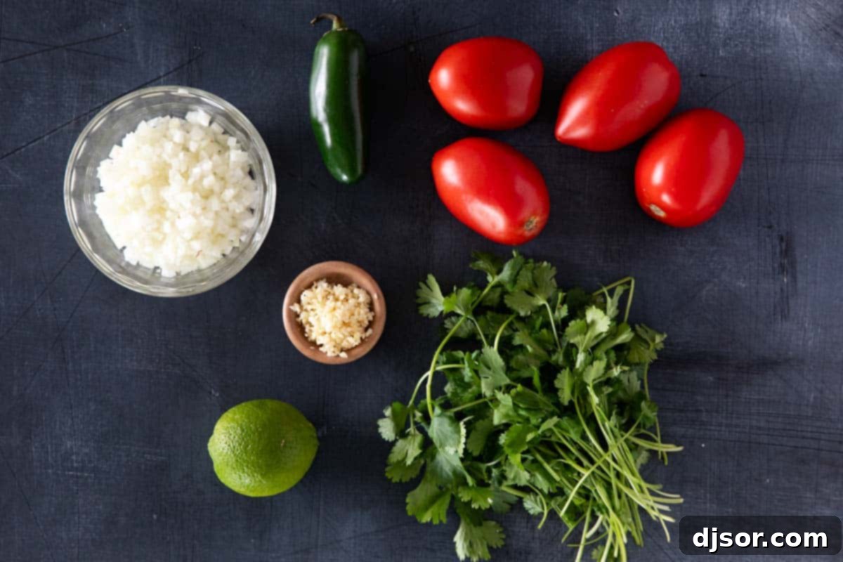 Various fresh ingredients for Pico de Gallo laid out on a cutting board: ripe Roma tomatoes, a red onion, a vibrant green jalapeño, fresh cilantro, garlic cloves, and bright green limes.