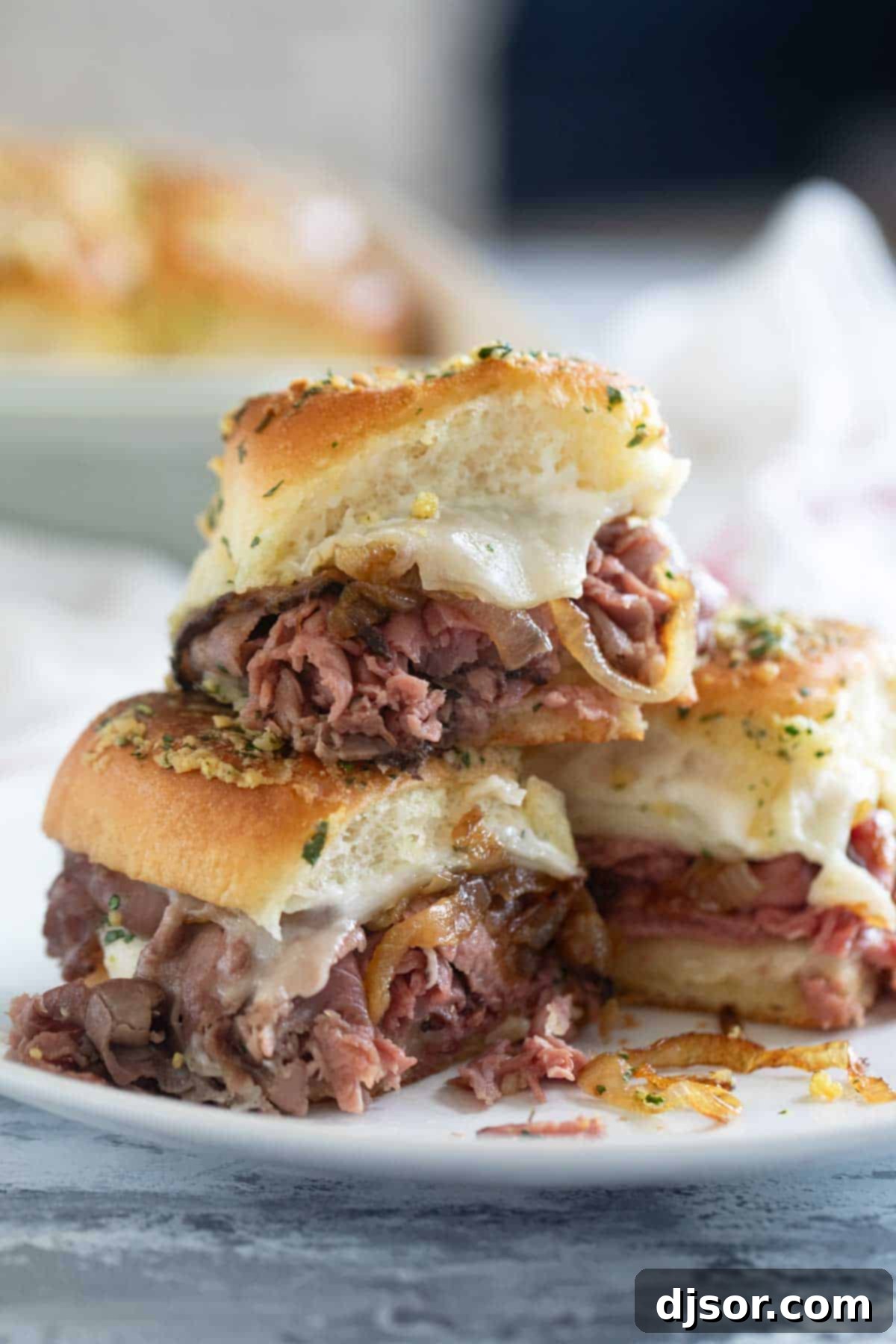 Three roast beef sliders, with one stacked on top of the others.