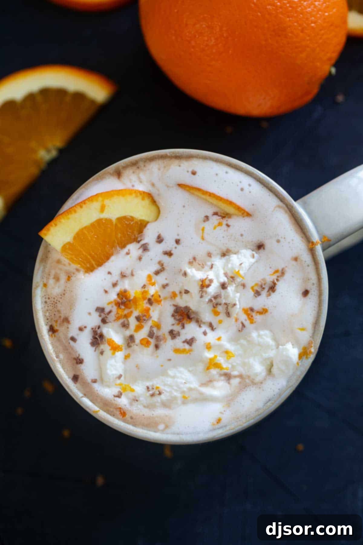 Orange hot chocolate topped with whipped cream and an orange slice.