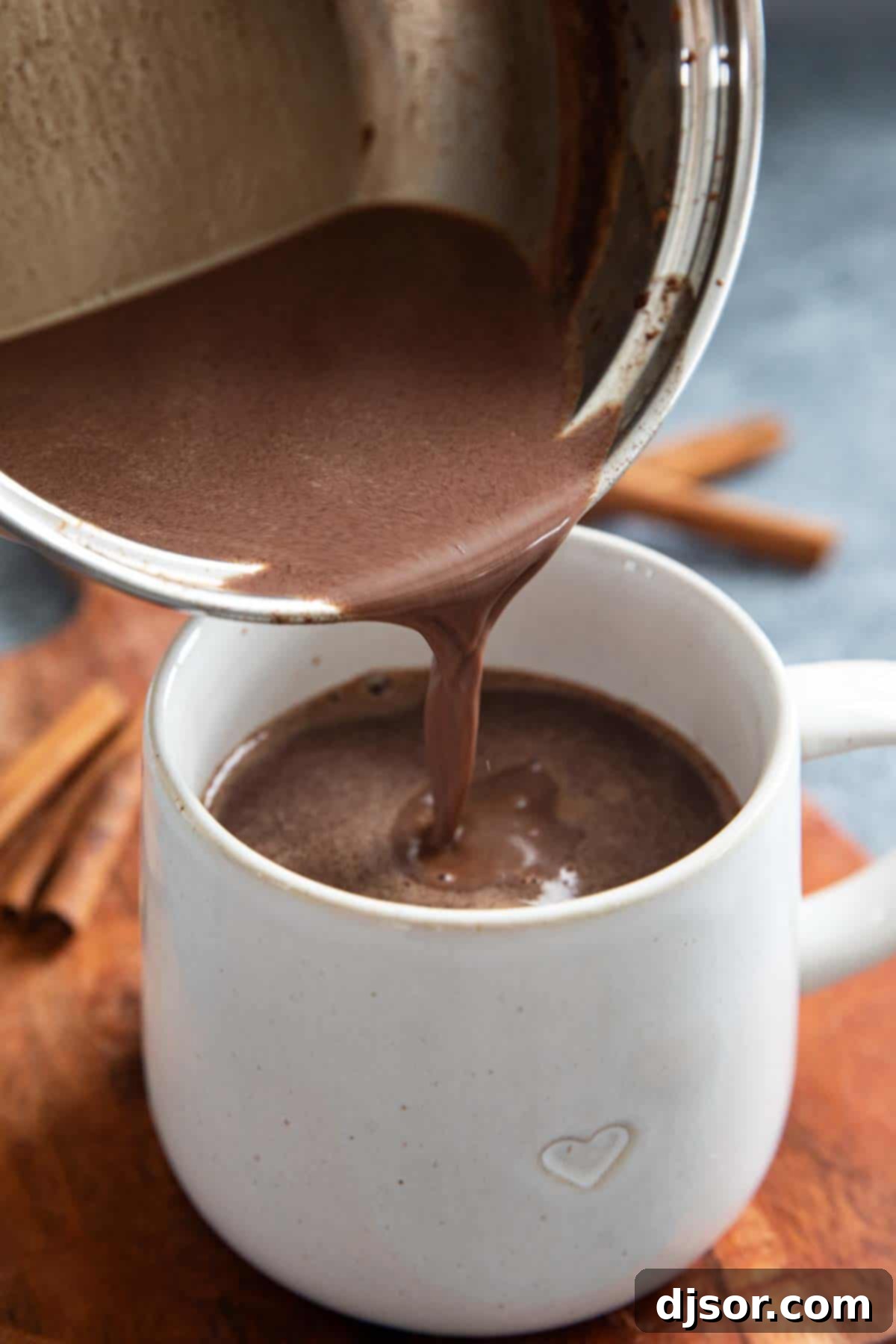 Velvety Mexican Spiced Chocolate 5 Pouring Mexican Hot Chocolate into a rustic mug, showing its rich, dark color and creamy texture.