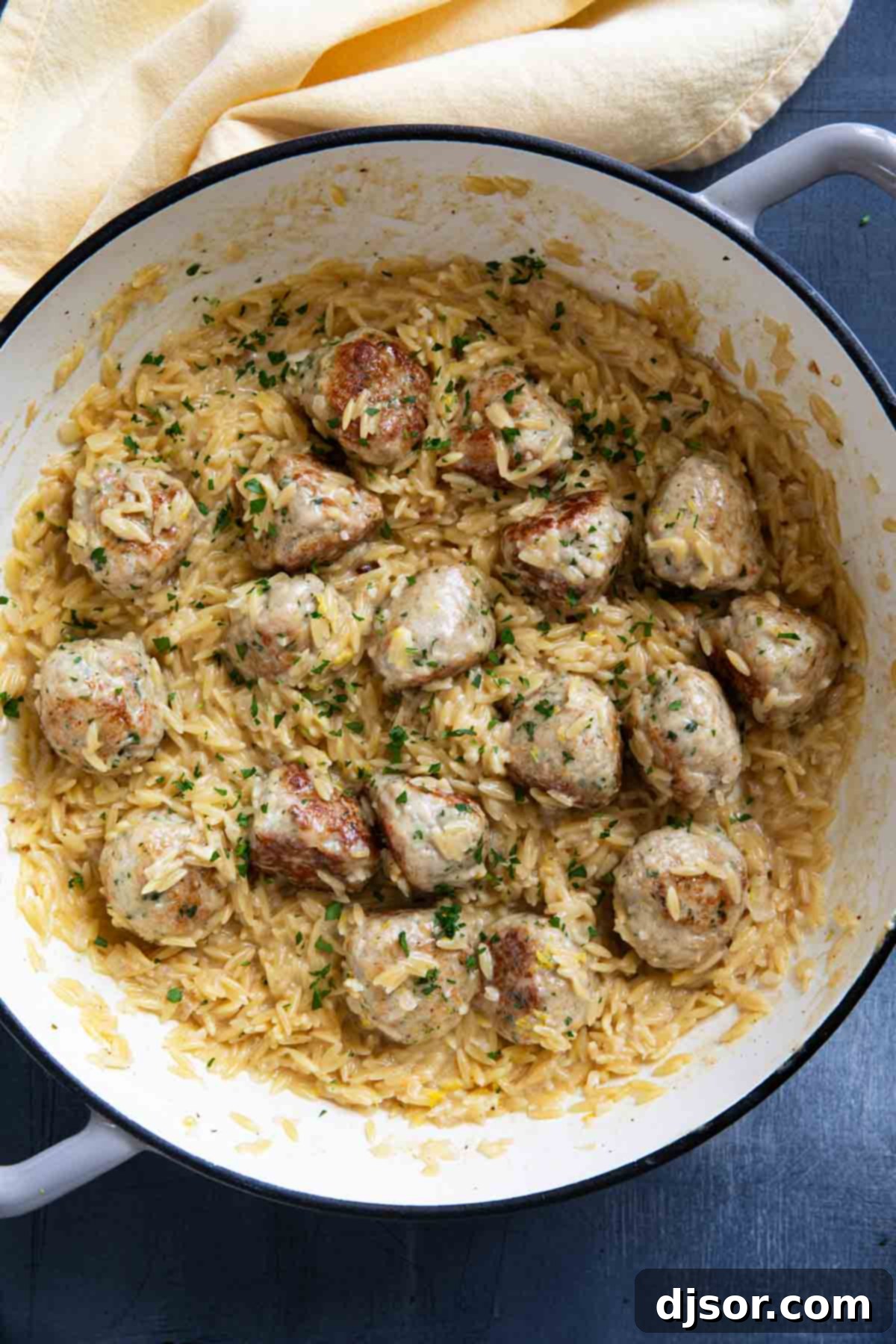 A complete one-pan meal featuring golden-brown chicken meatballs with creamy lemon orzo, perfectly cooked and ready to be enjoyed. The harmonious blend of flavors and textures makes this dish an inviting and comforting option for any meal.