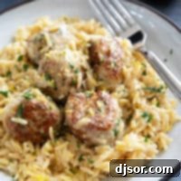 Plate filed with chicken meatballs on top of creamy lemon orzo.