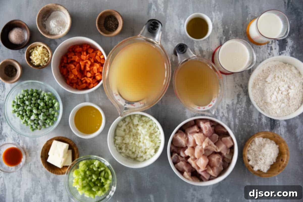 A vibrant selection of fresh ingredients laid out on a wooden cutting board, including diced carrots, celery, onion, chicken breasts, and herbs, ready for making chicken and dumplings.