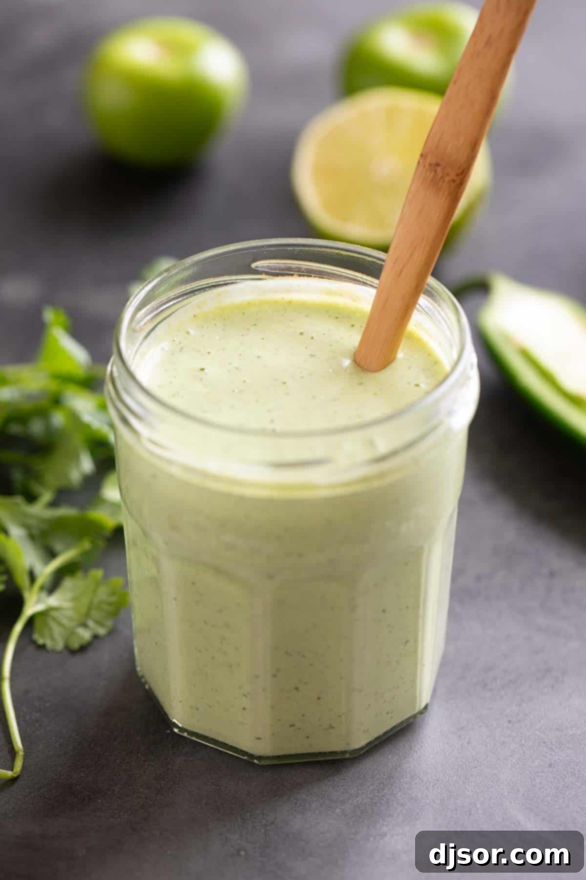 Tomatillo Ranch Dressing in a glass jar with a wooden spoon, ready to serve.