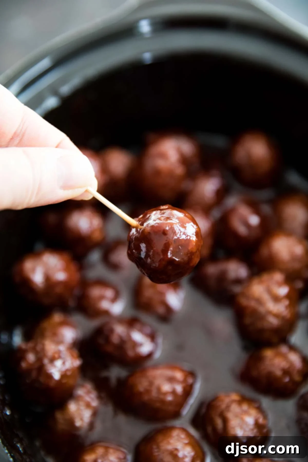 A single Crockpot BBQ Grape Jelly Meatball on a toothpick, showcasing the glossy glaze.
