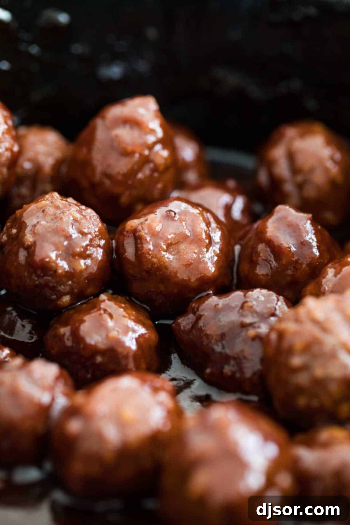 A large serving bowl filled with Grape Jelly BBQ Meatballs, garnished with fresh parsley.