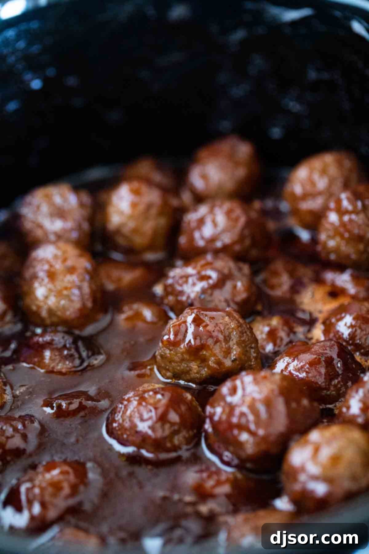 A crockpot brimming with cooked BBQ grape jelly meatballs, ready for serving.