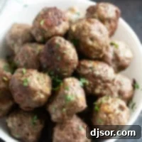Savory Baked Meatballs 8 Baked meatballs in a bowl sprinkled with parsley.