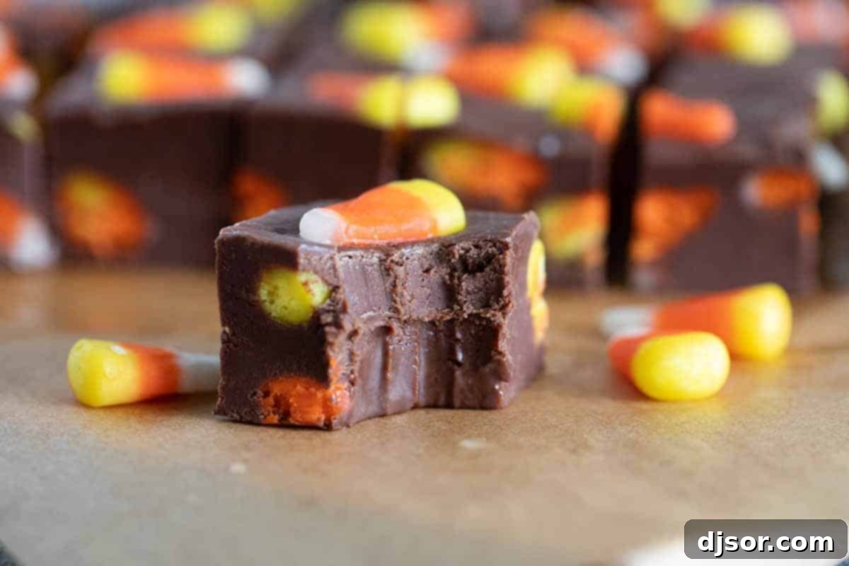 A single piece of homemade Candy Corn Fudge with a bite taken out of it, revealing the creamy texture and embedded candy corn pieces.
