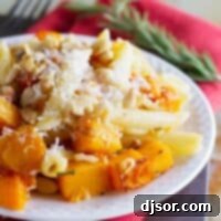 Plate filled with roasted butternut squash cubes and pasta, topped with parmesan cheese.