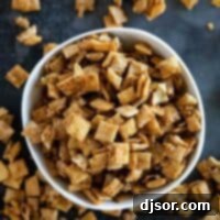 A bowl full of cinnamon caramel snack mix with more outside the bowl, presented invitingly.
