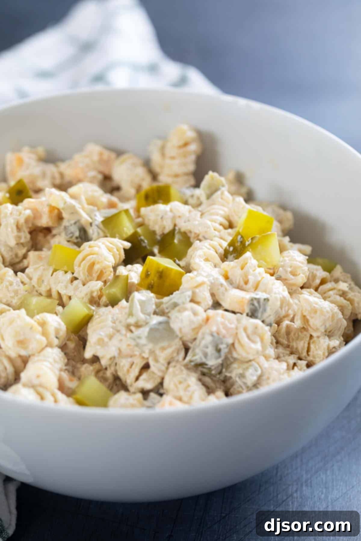 Briny Burst Pasta Salad 2 Serving bowl filled with creamy Dill Pickle Pasta Salad topped with fresh chopped pickles and dill.