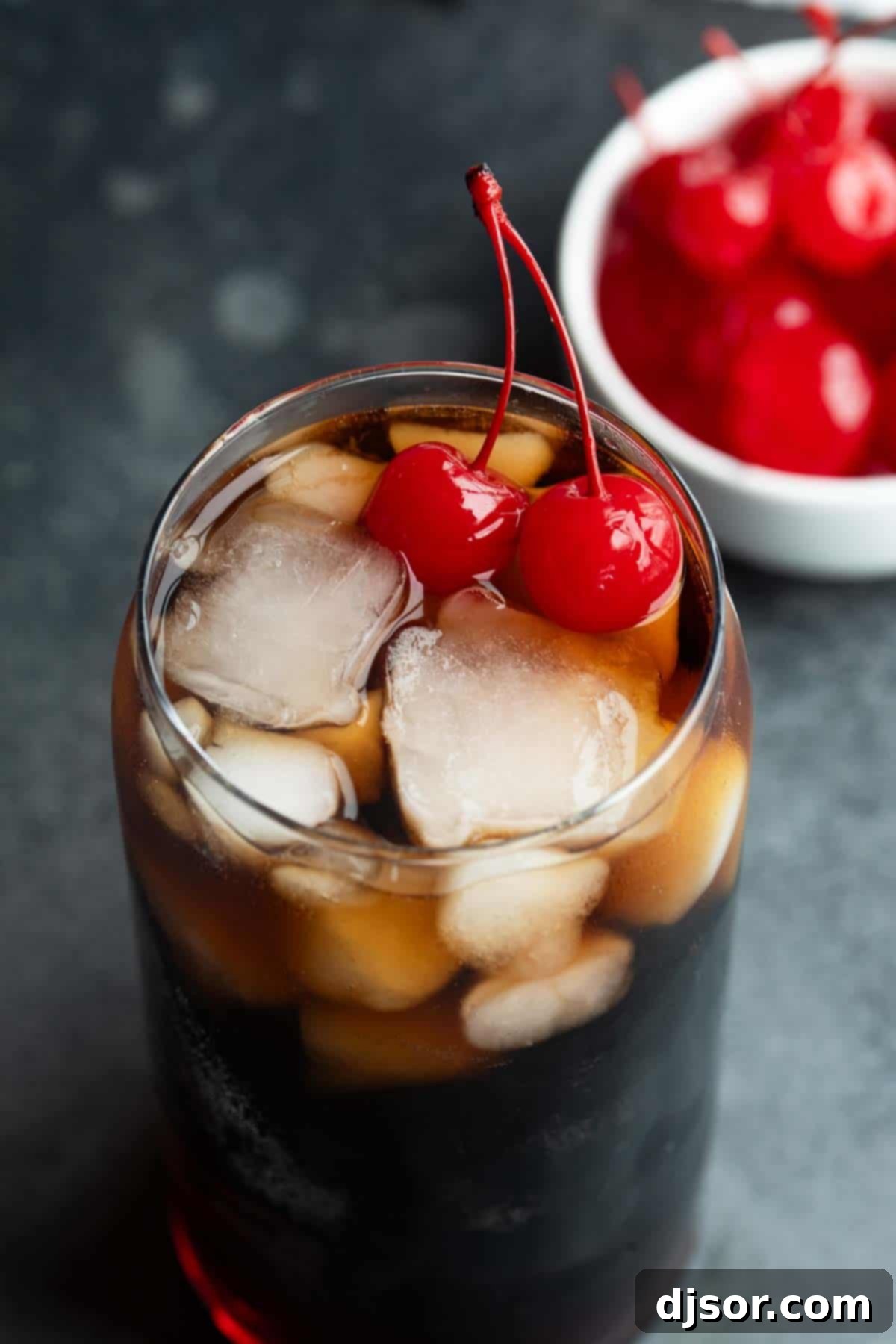 A perfectly made Roy Rogers Drink, showcasing the vibrant red color from grenadine and the fizzy cola, topped with ice and two maraschino cherries.