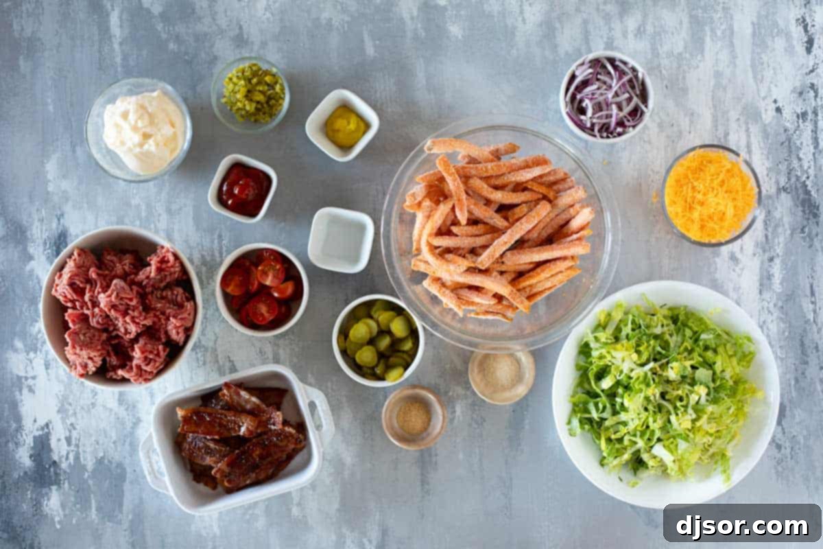 Various ingredients for assembling Burger Bowls, including ground beef, sweet potato fries, lettuce, bacon, cheese, and vegetables.