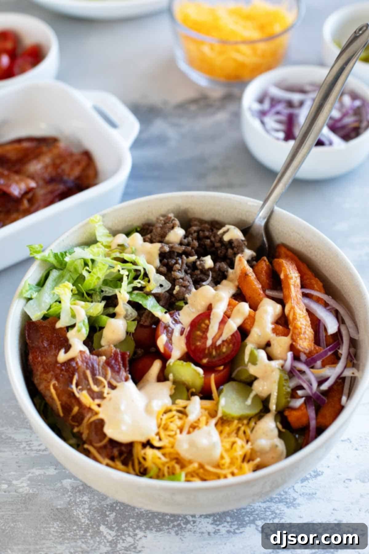A perfectly assembled Burger Bowl, garnished with fresh herbs and a generous drizzle of the signature special sauce, highlighting its readiness to eat.