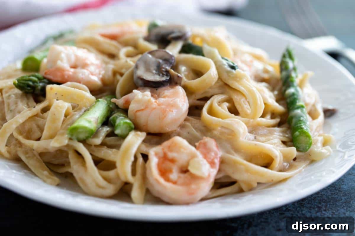 Shrimp Alfredo: An Impressive Yet Easy Homemade Pasta Dish A close-up of creamy Shrimp Alfredo pasta garnished with fresh parsley, alongside tender asparagus and succulent shrimp.
