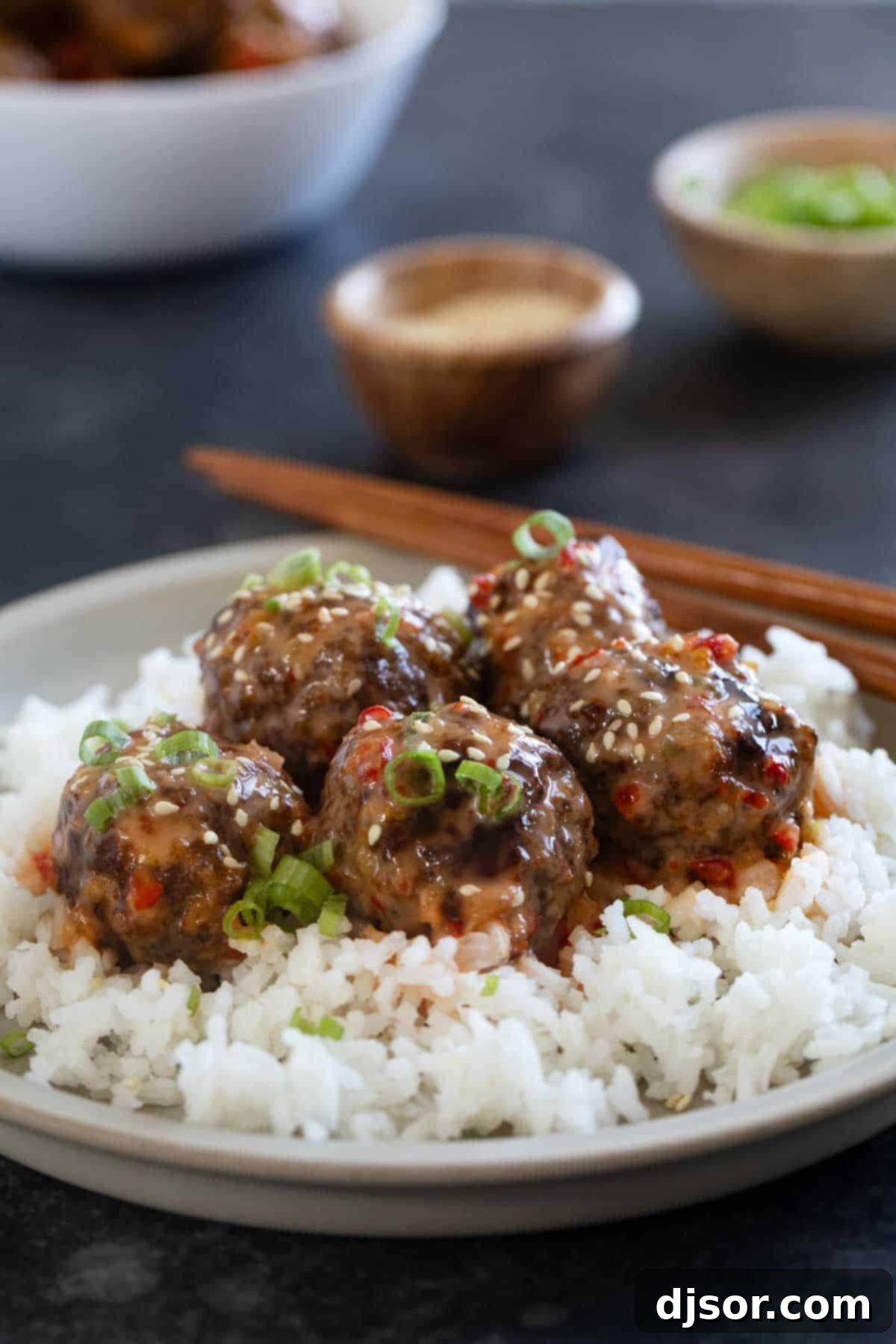 Firecracker Meatballs over rice, topped with green onions and sesame seeds.