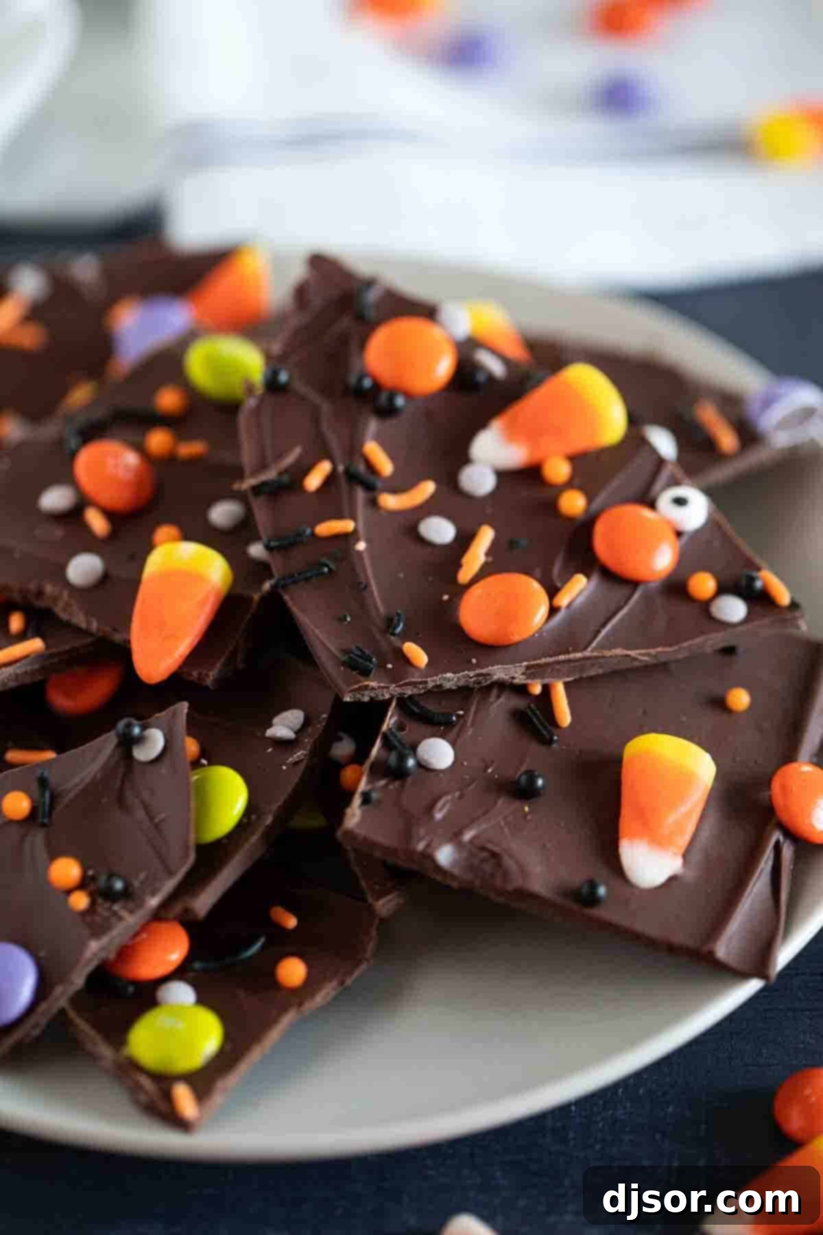 A festive plate piled high with colorful Halloween Candy Bark pieces, showcasing various candy toppings.