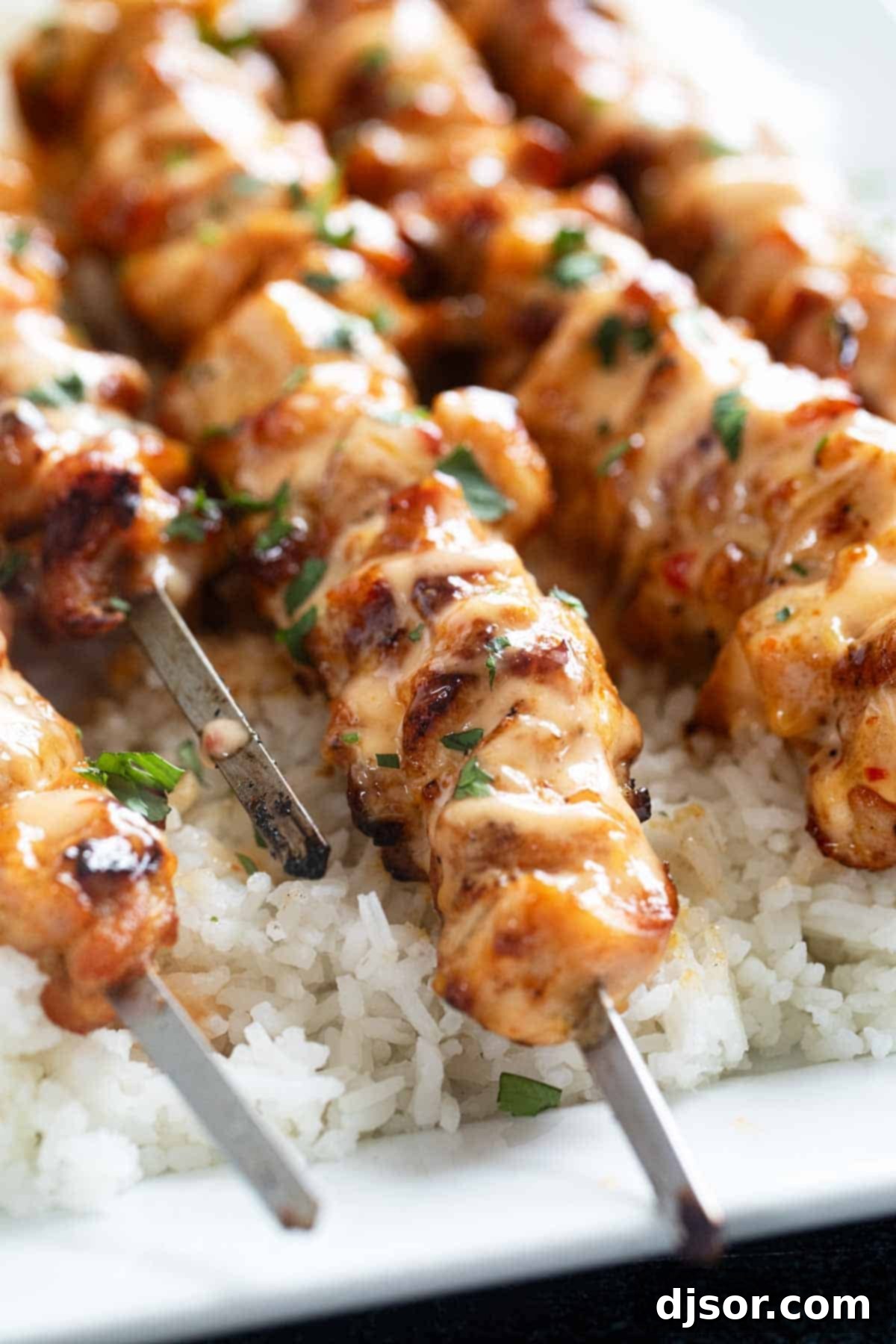 Ultimate Bang Bang Chicken Skewers 6 Cooked Bang Bang Chicken Skewers topped with fresh cilantro, ready to be served.