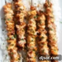 Ultimate Bang Bang Chicken Skewers 8 Bang Bang Chicken Skewers over rice on a platter.