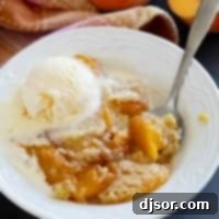 Bowl of peach dump cake topped with ice cream.