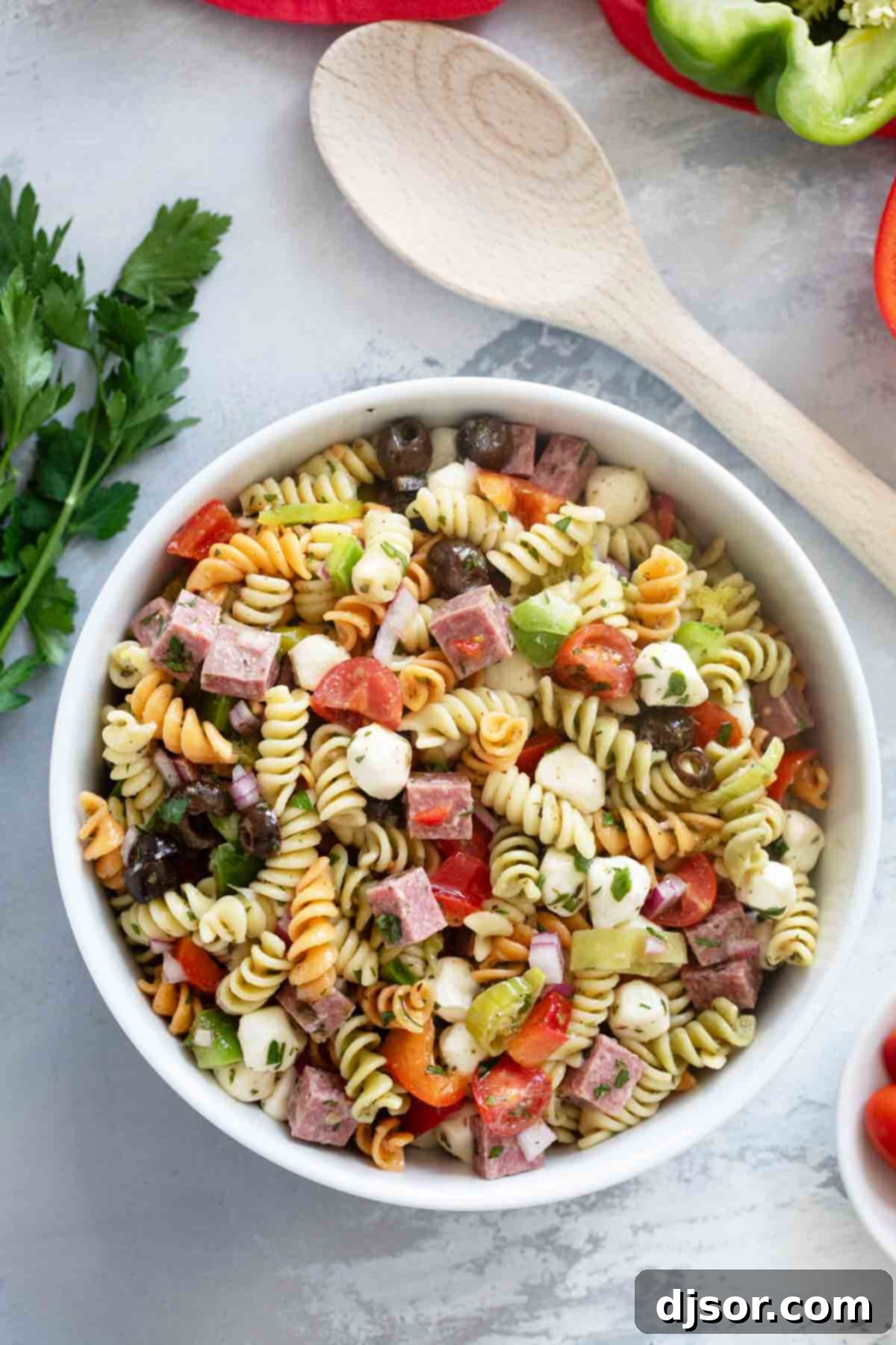 Italian Pasta Salad in a large serving bowl with a wooden spoon on the side.