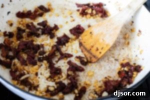 Sautéing onions and sun-dried tomatoes in a skillet.