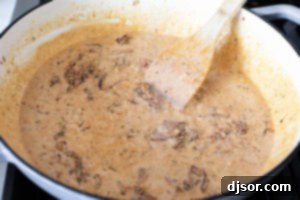 Adding cream and cheese to sun-dried tomatoes for salmon sauce.