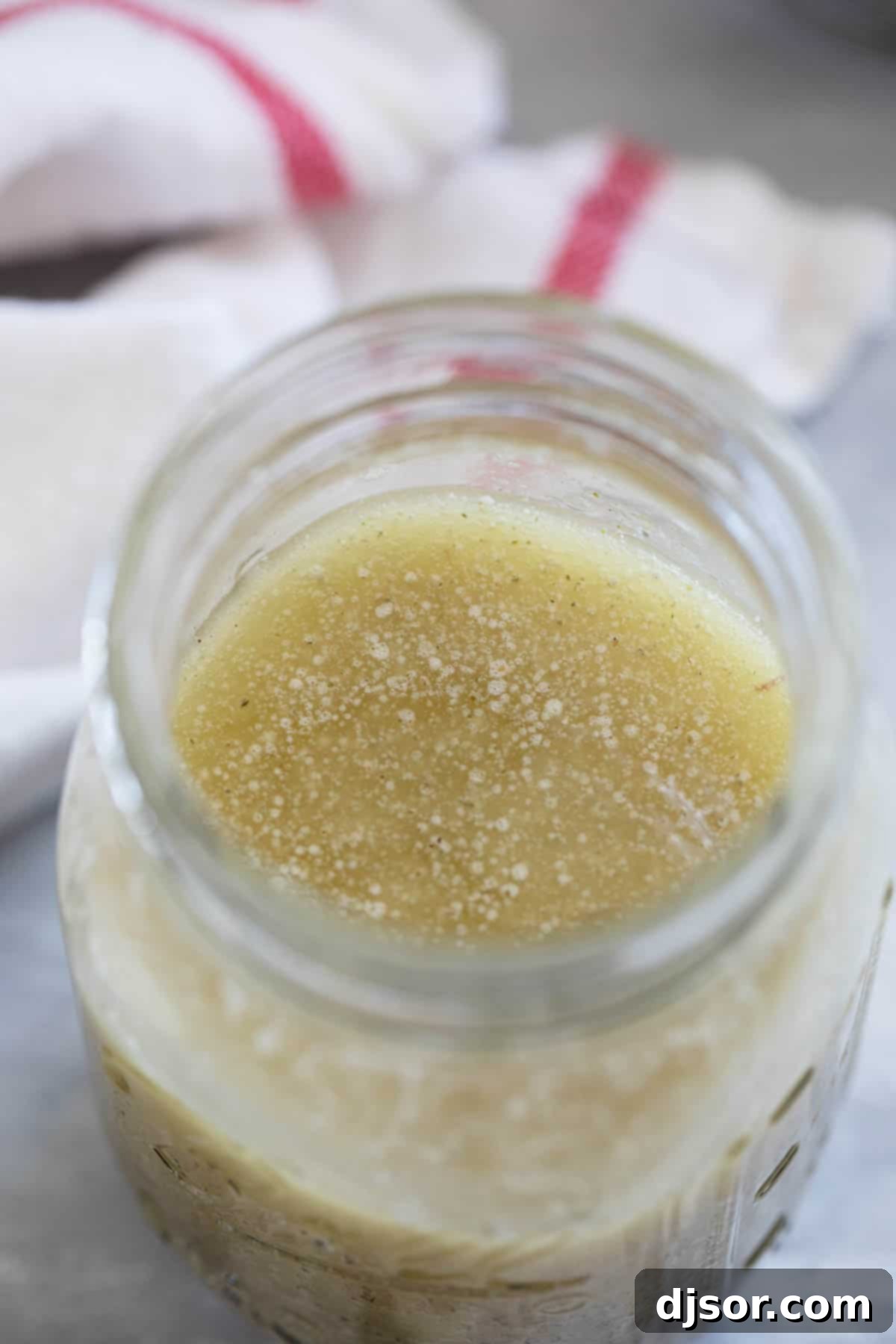 Freshly made copycat Olive Garden salad dressing stored in a transparent glass jar with a lid, ready for refrigeration and future use.