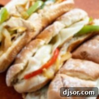 Ultimate Chicken Cheesesteak 10 Three Chicken Cheesesteak Sandwiches on a cutting board.