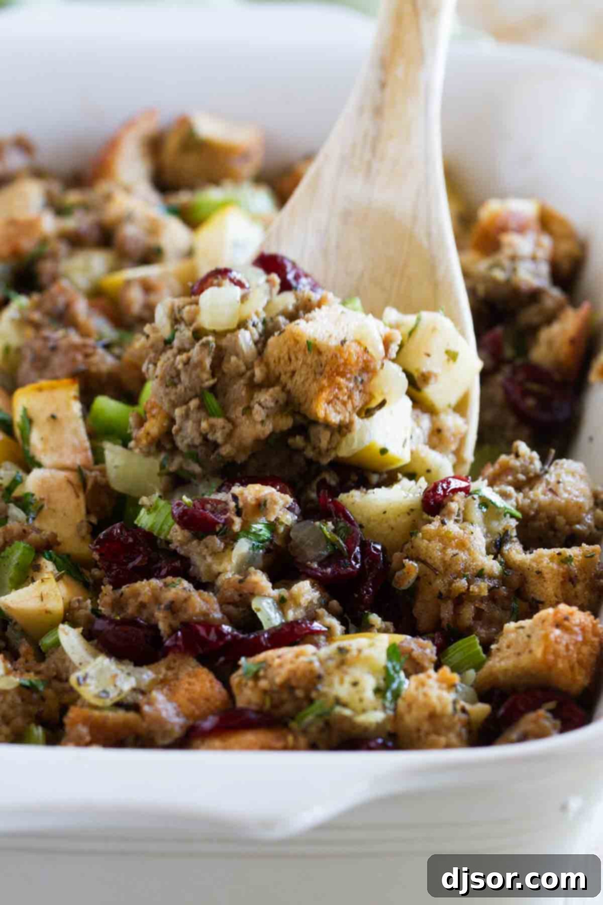 All of the flavors of fall come together in this Sausage Stuffing with Apples and Cranberries for the perfect holiday stuffing recipe. A generous spoonful of homemade Sausage Stuffing with Apples and Cranberries, showing the delicious mix of ingredients and a perfectly moist texture.