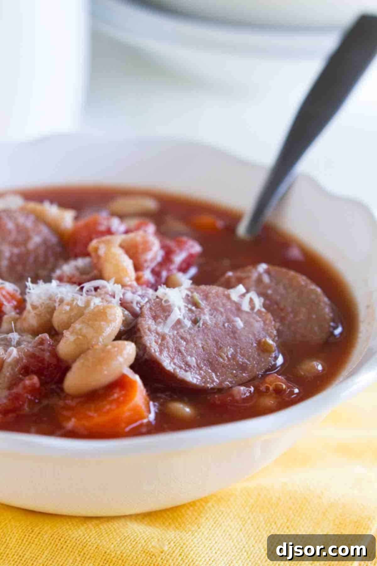 bowl of white bean soup with smoked sausage with a spoon in the bowl.