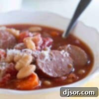 bowl of white bean soup with smoked sausage with a spoon in the bowl.