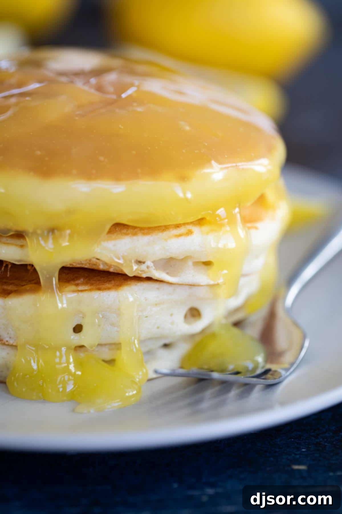Freshly prepared lemon sauce in a jar, alongside fresh lemons, highlights its vibrant citrus flavor. Homemade lemon sauce in a clear glass jar, with a fresh lemon and lemon slices in the background.