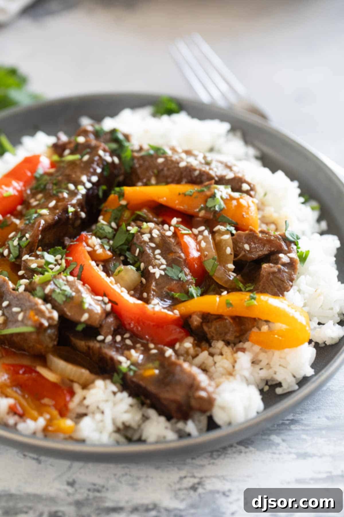 Fall-Apart Slow Cooker Pepper Steak 2 Serving of slow cooker pepper steak over rice, topped with cilantro and sesame seeds.
