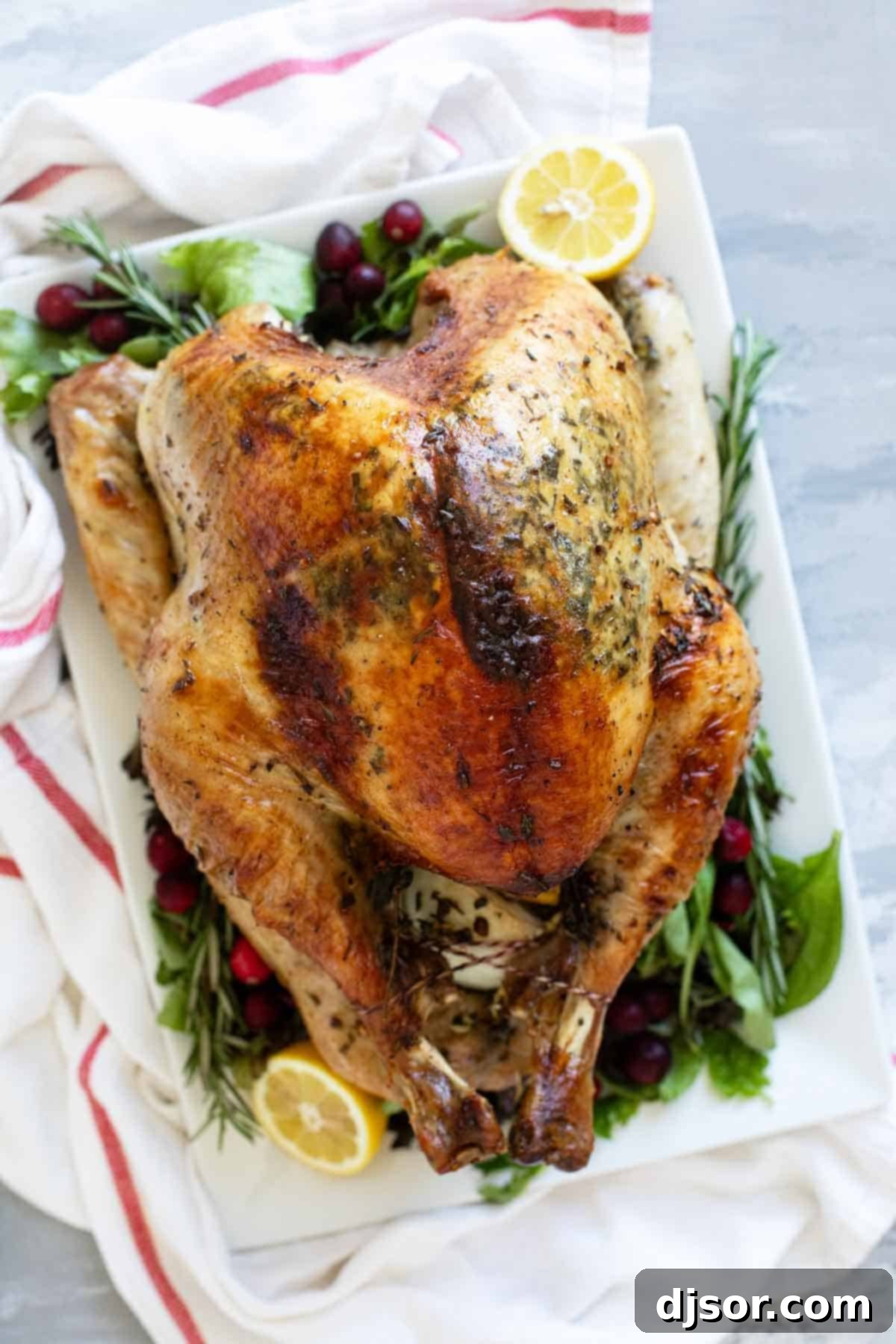 The Ultimate Roast Turkey 2 A perfectly roasted whole turkey, golden brown and garnished with fresh herbs, resting on a rustic wooden serving platter, ready for carving.