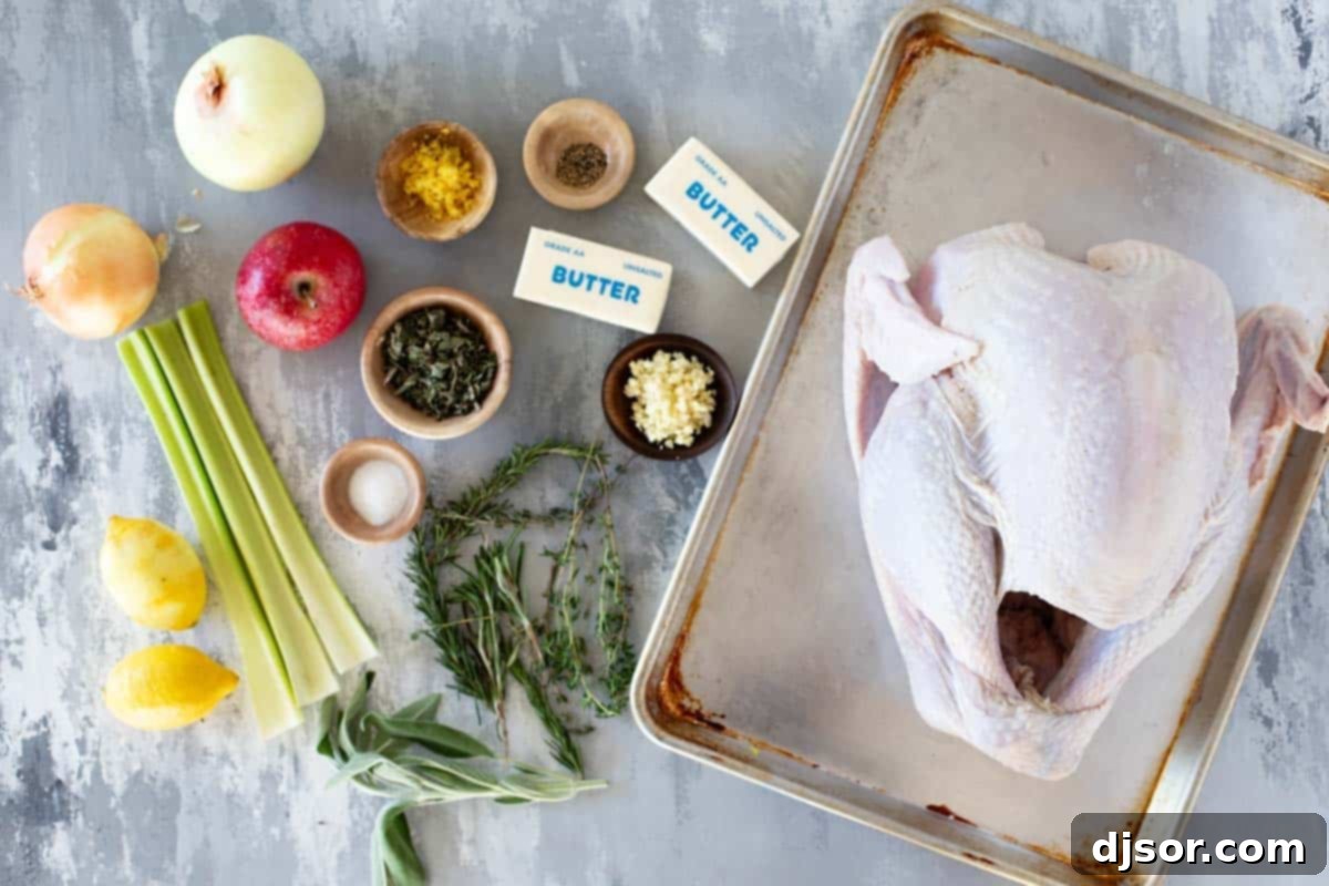 The Ultimate Roast Turkey 3 A selection of fresh ingredients laid out on a wooden board, including a whole turkey, softened butter, garlic cloves, fresh sprigs of rosemary, thyme, and sage, lemons, onions, celery, and an apple, all ready for the roast turkey recipe.
