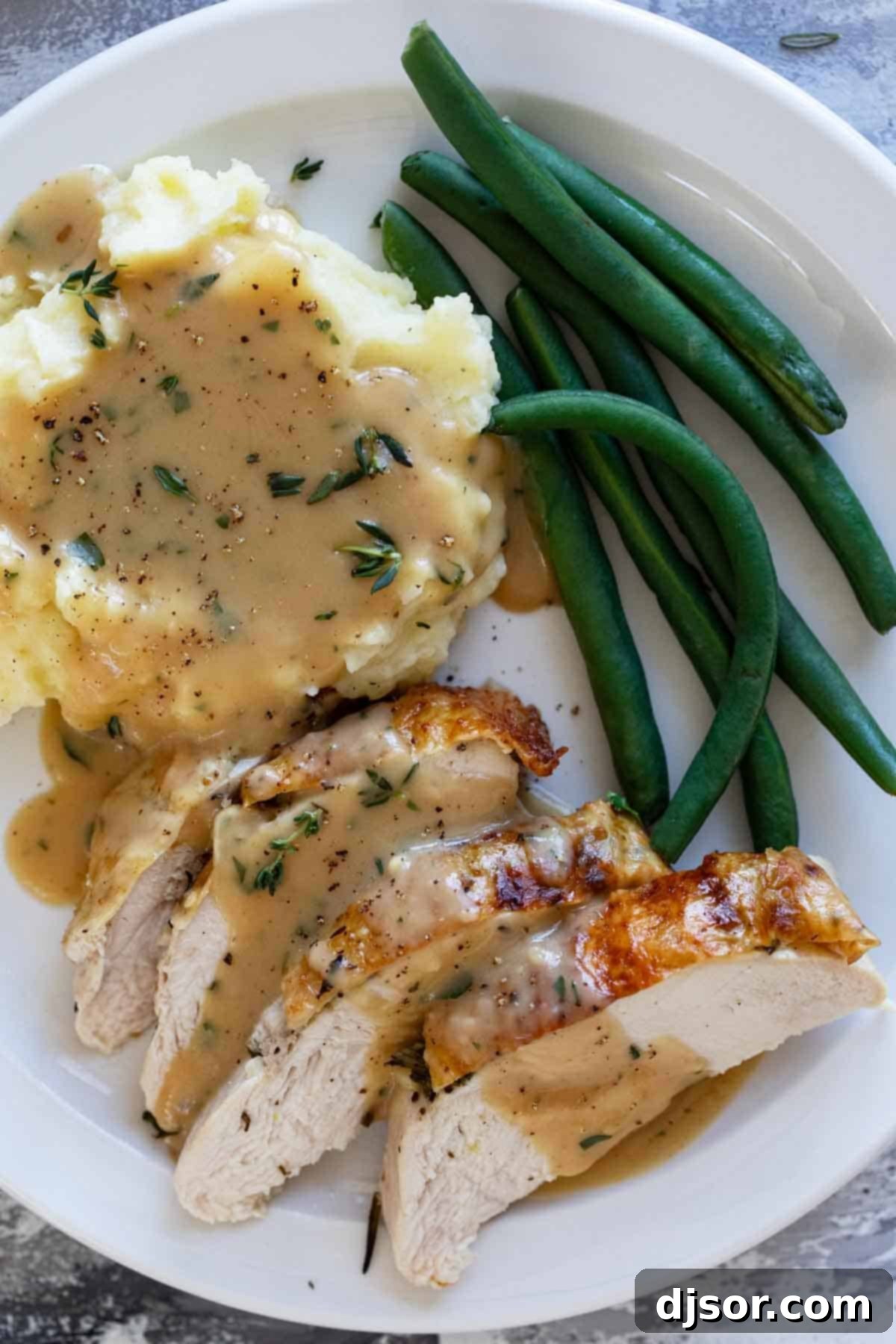 The Ultimate Roast Turkey 9 A festive holiday plate featuring slices of succulent roast turkey, generously covered with gravy, alongside creamy mashed potatoes and vibrant green beans, showcasing a complete Thanksgiving meal.