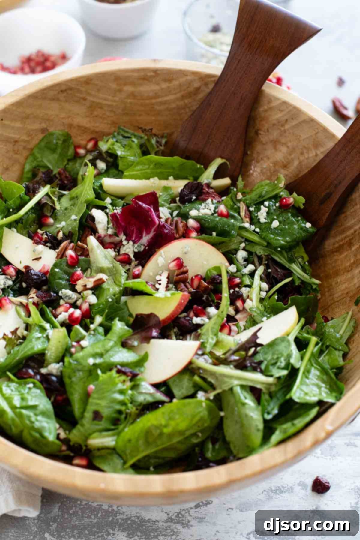 A beautifully arranged Thanksgiving Salad, showcasing crisp apples, vibrant pomegranate seeds, and a glistening apple cider vinaigrette.
