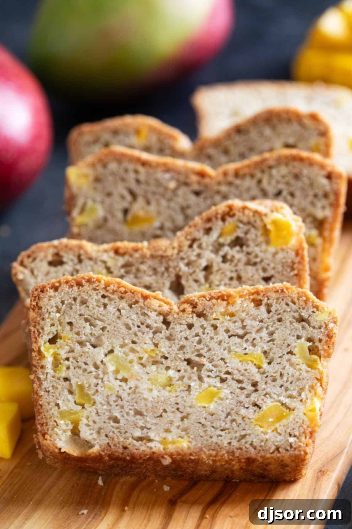 Slices of Easy Mango Bread stacked next to each other, showcasing its golden crust and visible mango chunks.