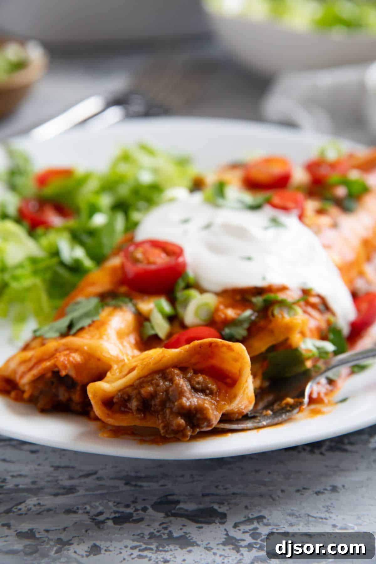 Cheesy Beef Enchilada Bake 9 A single ground beef enchilada being lifted with a fork, showing the cheesy, beefy interior.