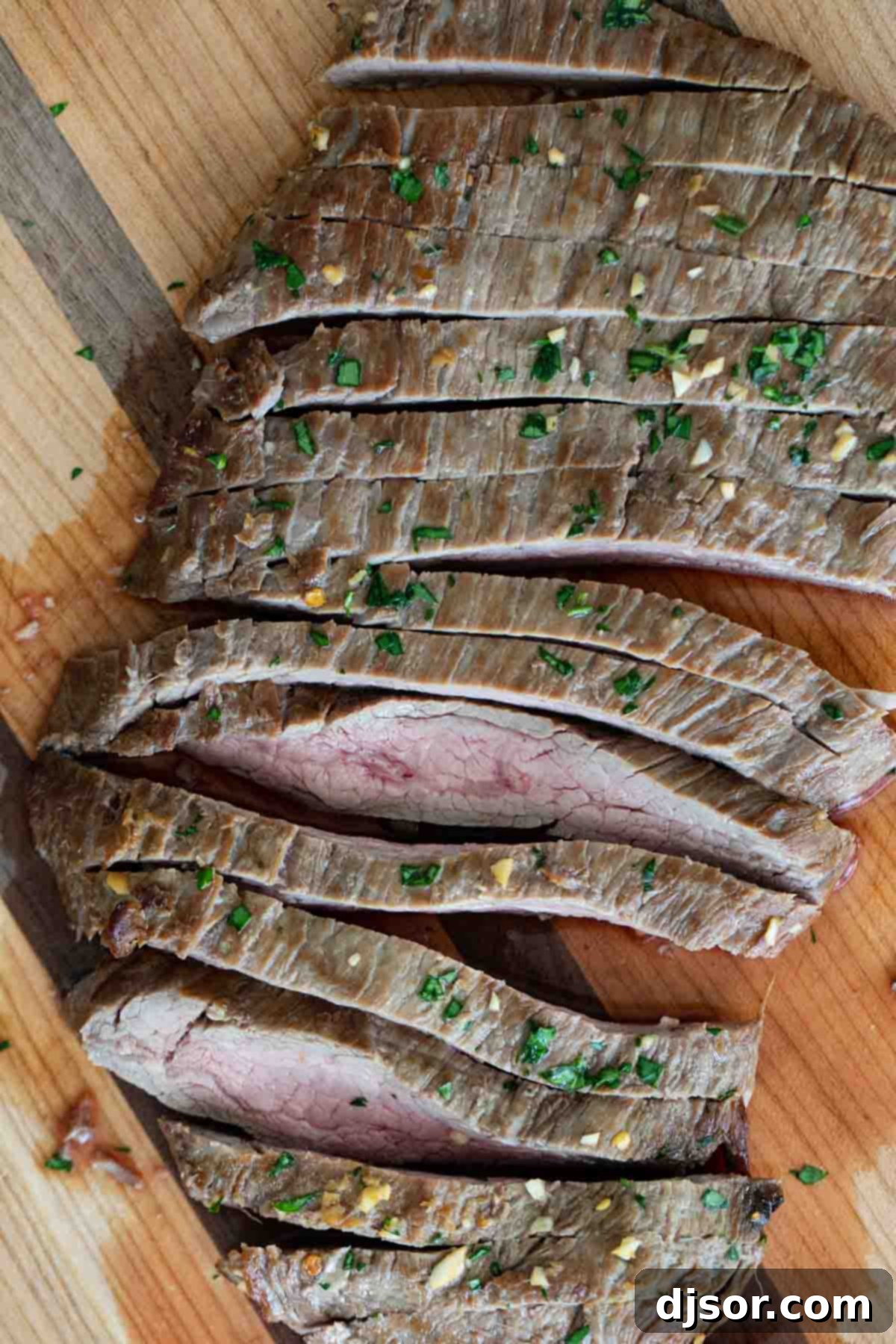 Overhead view of a perfectly sliced, tender flank steak showing the grain.