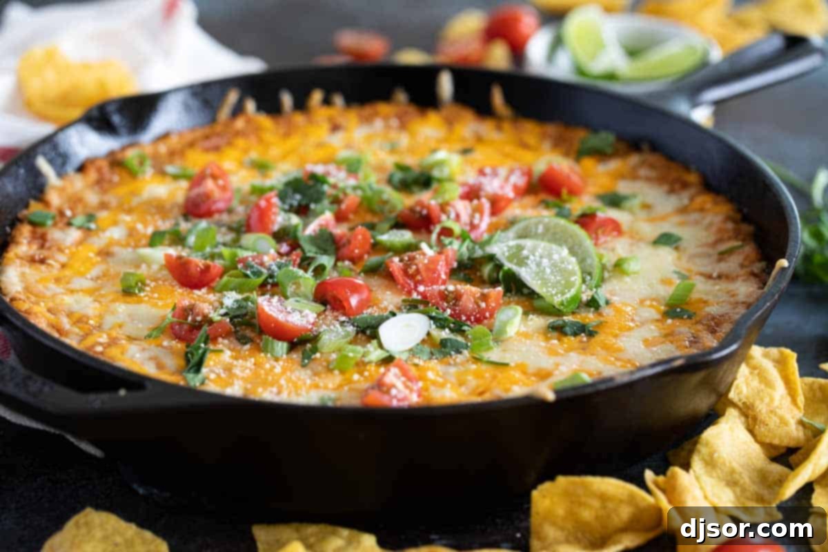 The Ultimate Easy Cheesy Bean Dip Recipe A warm skillet of cheesy bean dip topped with melted cheese and fresh garnishes, ready to be served with tortilla chips.