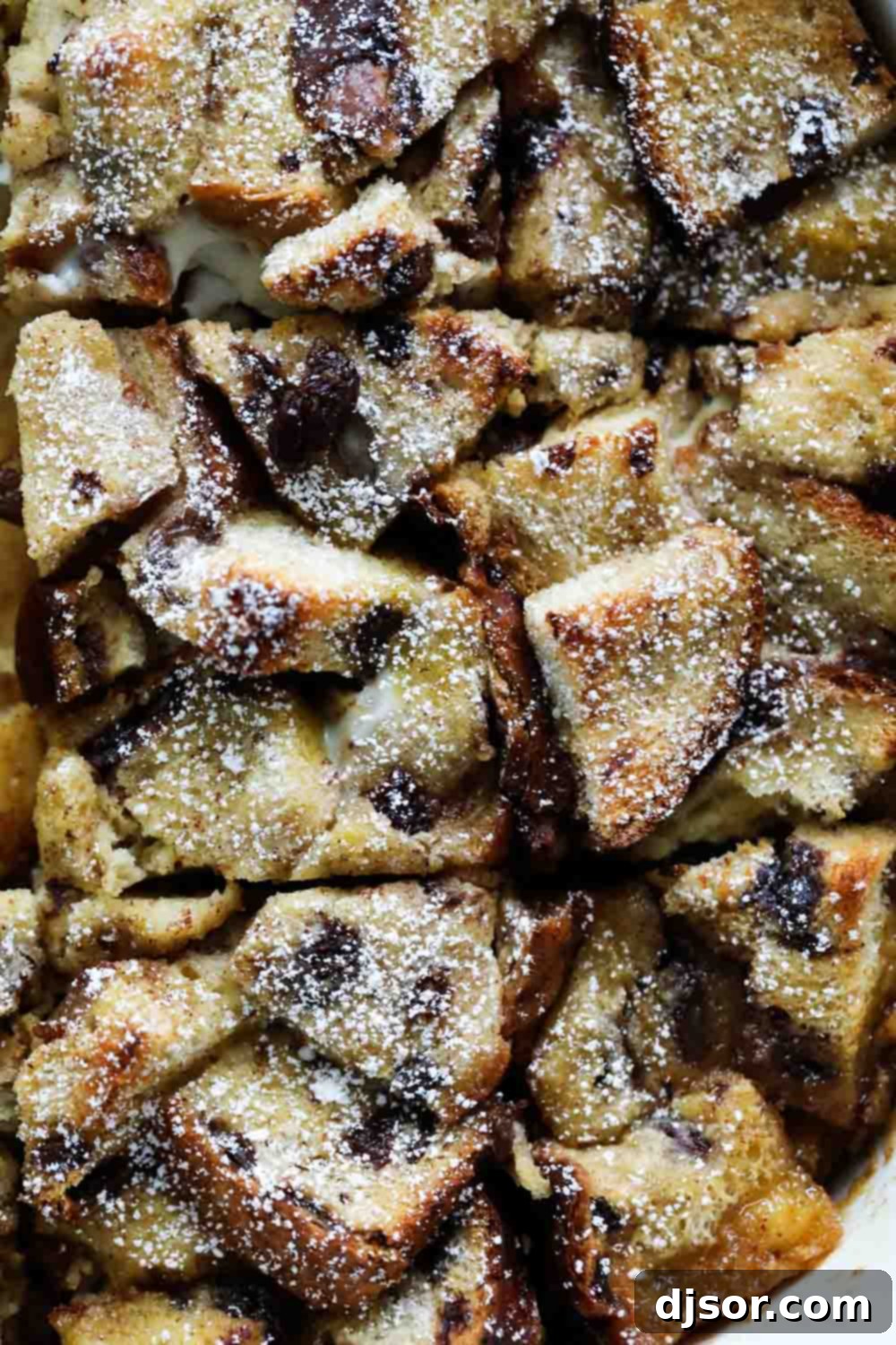 Baked French Toast Casserole with Apples and Raisins topped with powdered sugar.