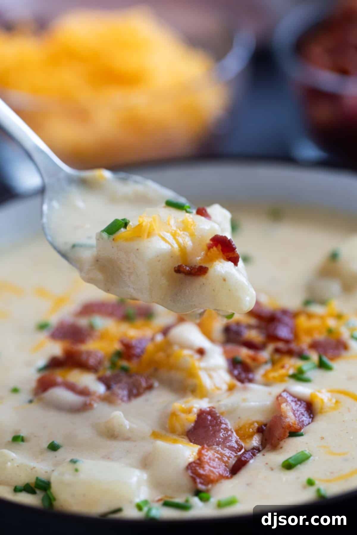 Loaded Baked Potato Soup 9 Spoon filled with baked potato soup, topped with bacon and cheese.