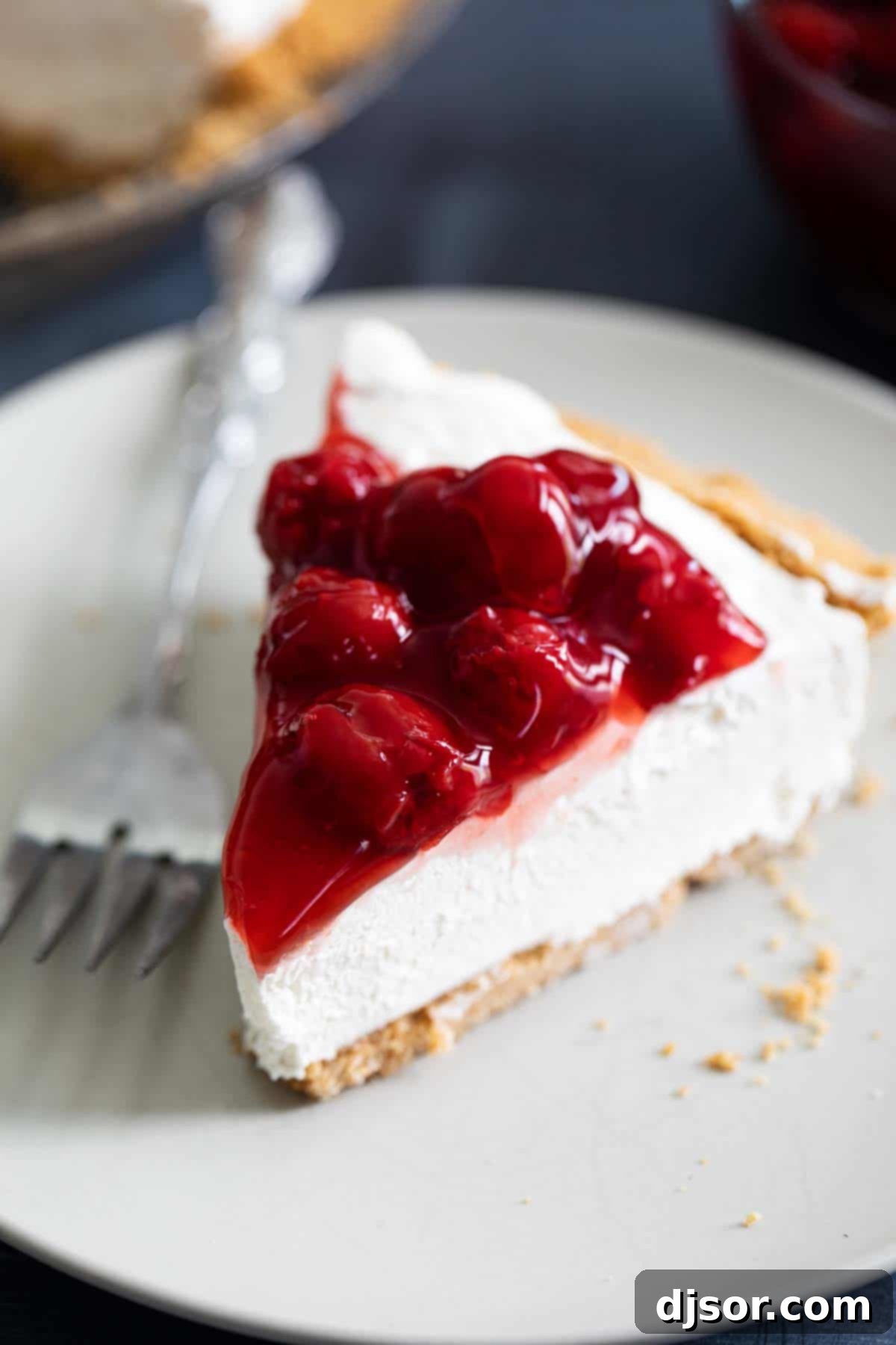 Creamy and smooth, this No Bake Cheesecake is the perfect summer dessert. A sweet cheesecake filling is set inside a graham cracker crust for an irresistible classic dessert. Top it with pie filling to take it up another notch! Slice of No Bake Cheesecake with Cherry Topping