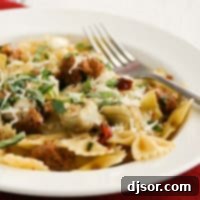 A beautifully presented bowl of Pasta with Italian Sausage, Artichokes, and Sun-Dried Tomatoes, garnished with fresh basil.