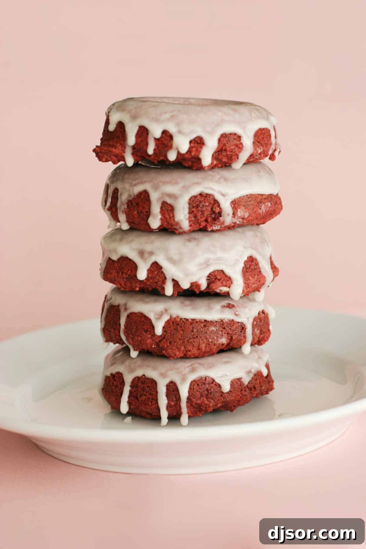 A stack of five vibrant Baked Red Velvet Donuts, each perfectly glazed and ready to be enjoyed, showcasing the inviting texture and rich color of this delightful treat.