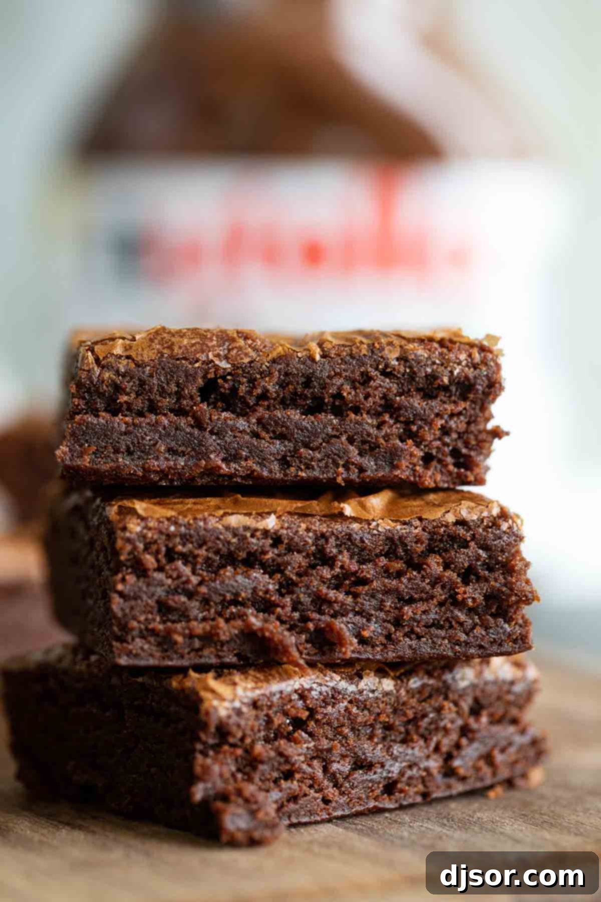 Three decadent Nutella brownies, stacked artfully on top of each other, highlighting their thick, fudgy texture and rich brown color.